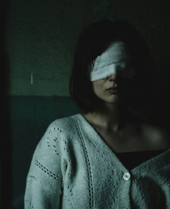A woman with a bandage on her head standing in a dark room