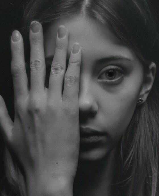woman covering half of her face grayscale photography