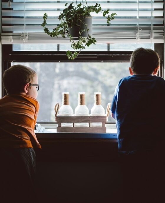 two boys standing in front of window