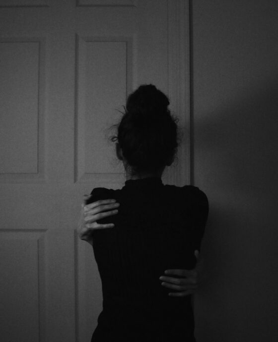 woman in black dress standing near white wooden door