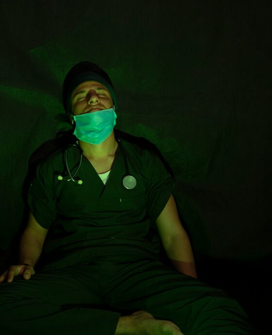 man in black button up shirt and black pants sitting on black textile