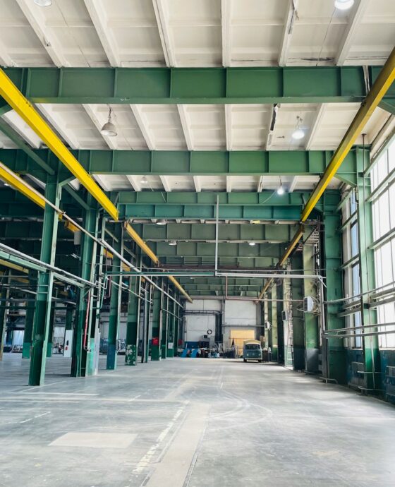 an empty warehouse with yellow and green pipes